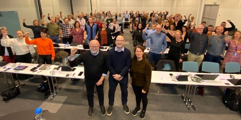 Representantskapet i Utdanningsforbundet stående med nevene i været, stående mot fotograf. 