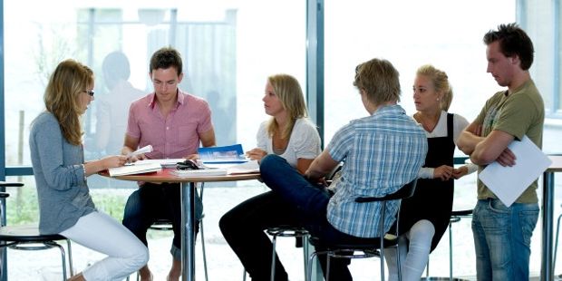 En gruppe ungdommer sitter rundt et bord og diskuterer. Foto.