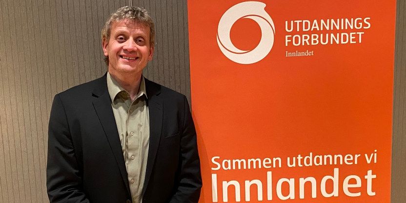 Bildet viser Lars Frode Finstad stående ved siden av en roll ut fra Utdanningsforbundet hvor det står "sammen utdanner vi Innlandet"