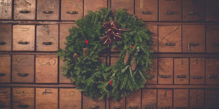 Bildet viser en julekrans som henger på en vegg med mange skuffer.