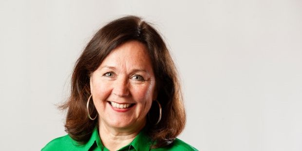 Kvinne i grønn bluse som smiler. Foto.