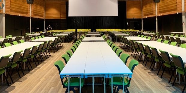 Langbord og stoler er satt fram til landsmøtedelegatene. I enden av rommet er det en stor skjerm. Landsmøtesalen er tom for mennesker. Illustrasjonsfoto.
