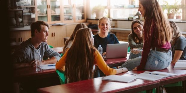 En gruppe studenter samtaler uformelt i et klasserom. Illustrasjonsfoto