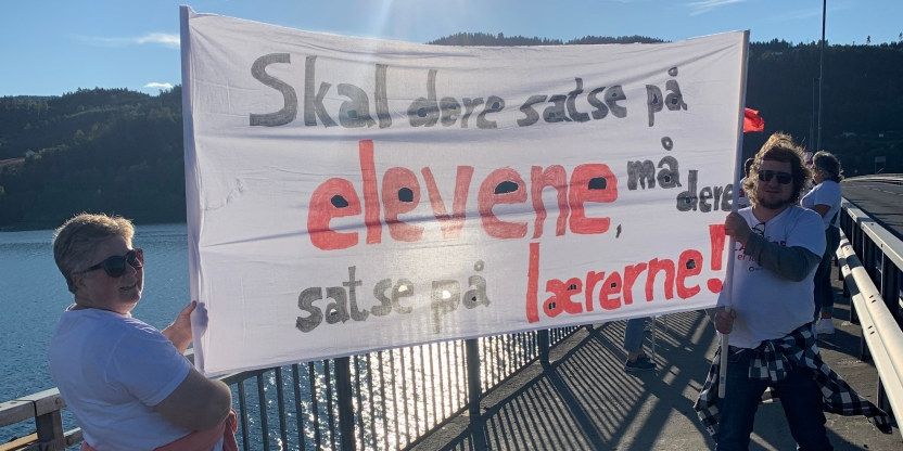Bilde av stine Grinden Pettersen og Roar Busterud som holder en banner med teksten: skal dere satse på elevene, må dere satse på lærerne