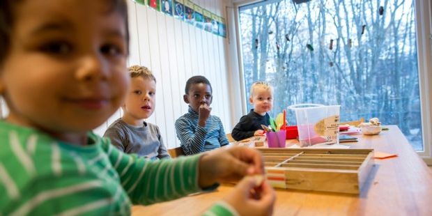 4 children eating and sitting around a table. Photo.