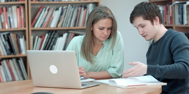 To studenter samarbeider foran en pc. Illustrasjonsfoto.