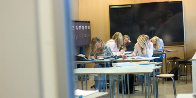 Biletet viser eit klasserom med nokre få elevar og fleire tomme pulter.
