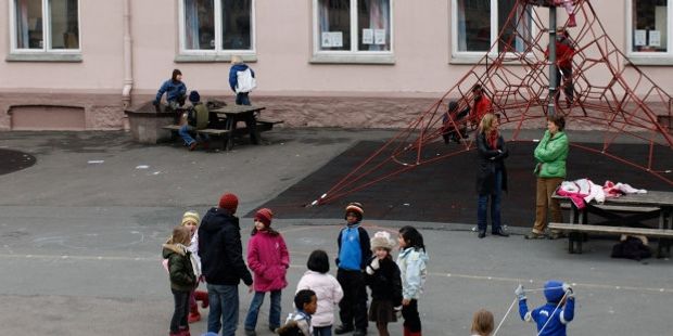 Mange barn leker i en skolegård. Foto.