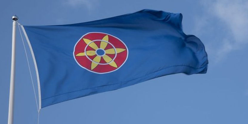 Kvenflagg i vinden mot en blå himmel.