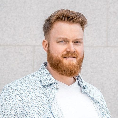 Portrett av en blid mann i midten av 20-årene med oransje hår og skjegg.