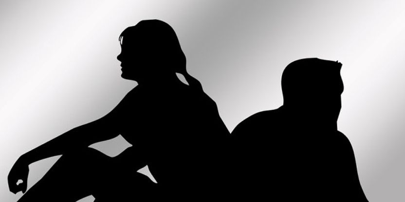 Sort hvitt bilde med to personer som sitter med ryggen mot hverandre