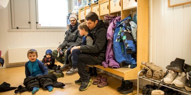 To barnehagelærere hjelper barn med å ta på seg utetøy.