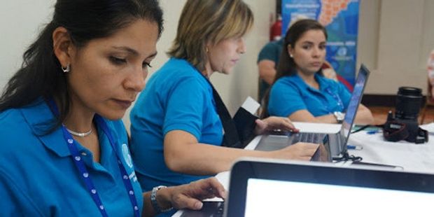 Bildet viser tre kvinner med datamaskiner som leder et møte. Foto.