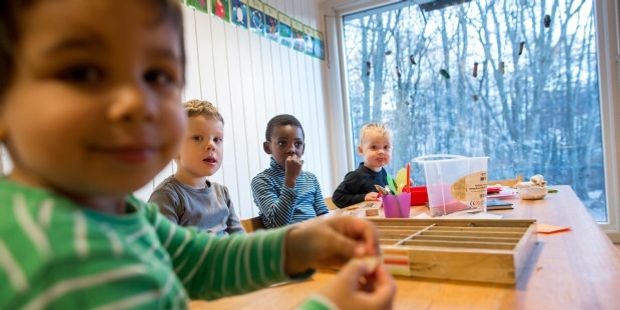 4 barn sitter rundt et bord og spiser. Foto.