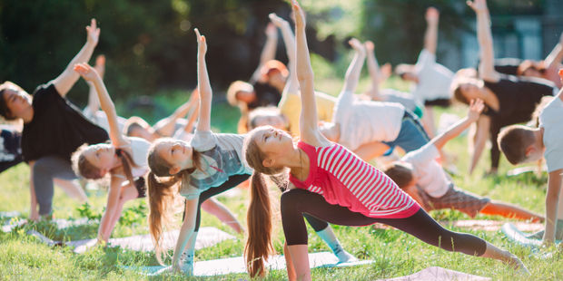 Barn som gjør yoga på en plen