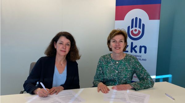 twee vrouwen ondertekenen contract zittend achter een tafel