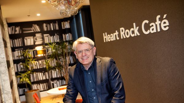 Man, zittend op tafel voor grote boekenkast in het Heart Rock Café