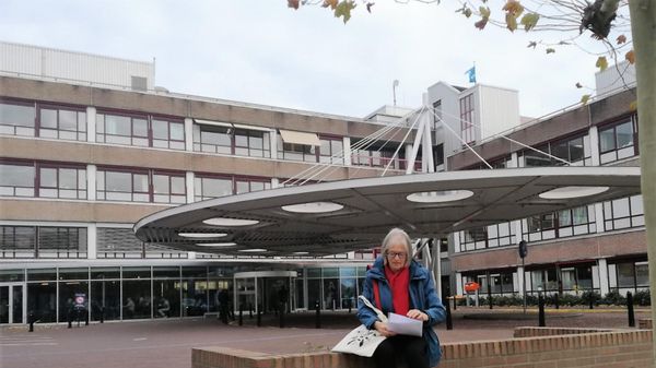 vrouw zit voor gebouw