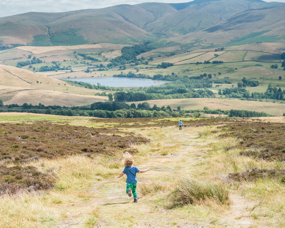 Boys running down Binsey with lake in background, Lake District photographers