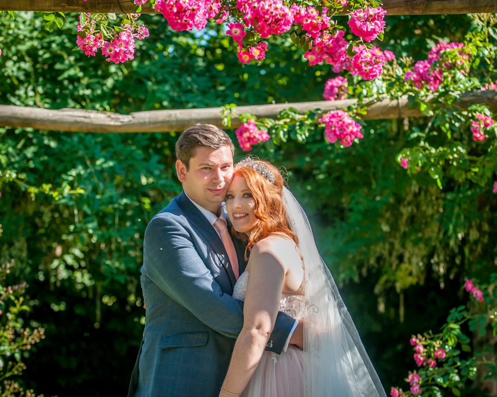 Bride and groom under floral arch in castle grounds, Ripley Castle weddings, Yorkshire wedding photographers