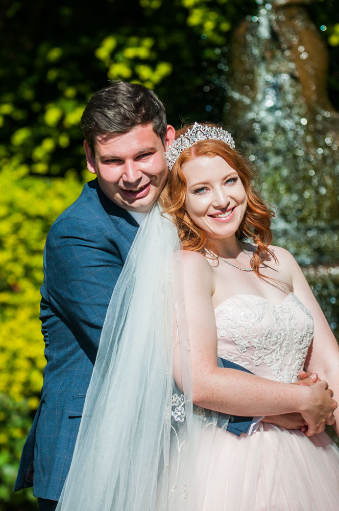 Bride and groom cuddling with fountain in background, Ripley Castle weddings, Yorkshire wedding photographers