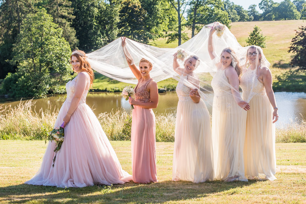 Bride and bridesmaids under veil in castle grounds, Ripley Castle weddings, Yorkshire wedding photographers