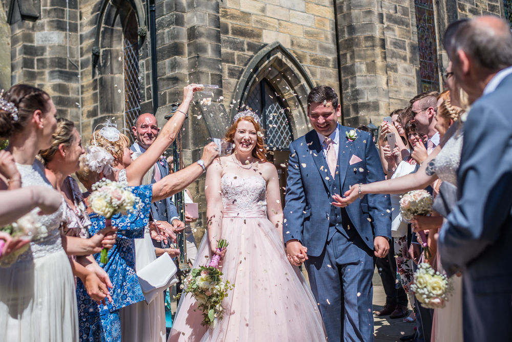 Bride and groom walk through confetti, Burley in Wharfedale church, Yorkshire wedding photographers