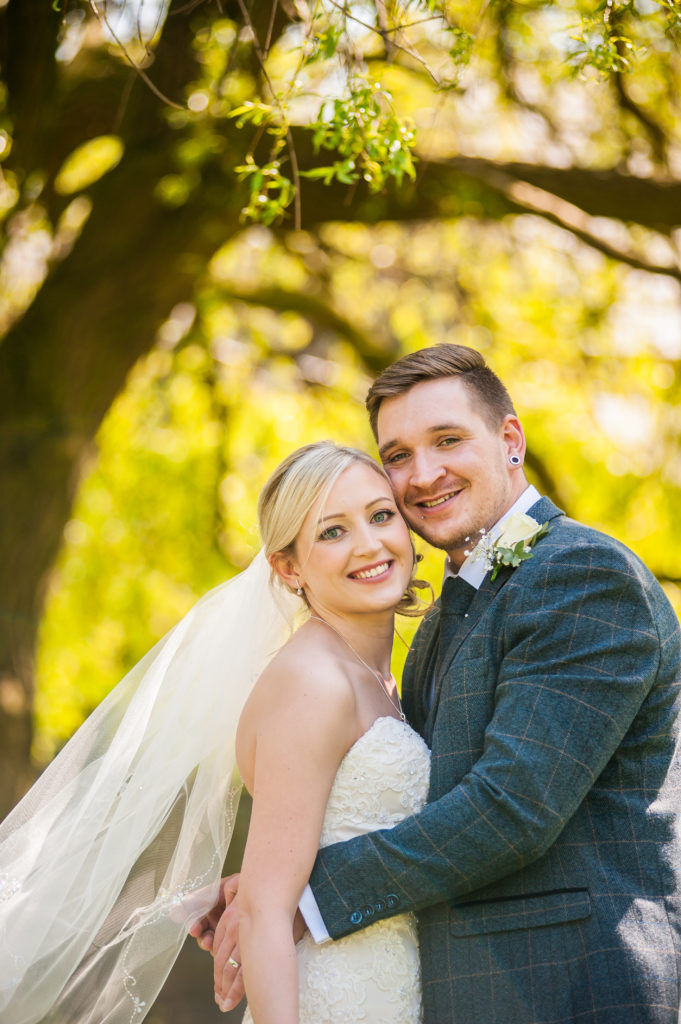 Bride and groom posing under tree in church yard, Wortley Hall, Sheffield wedding photography