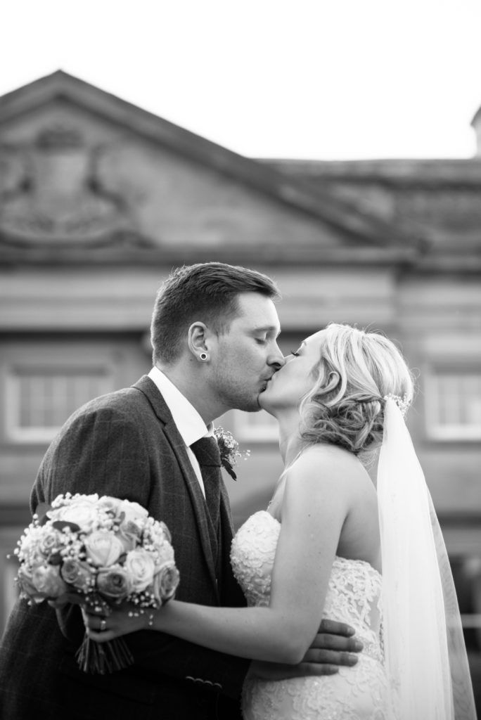 Bride and groom kiss with hall in background, Wortley Hall, Sheffield wedding photography