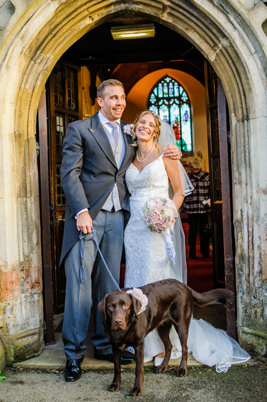 Bride and groom with dog outside Whiston Church