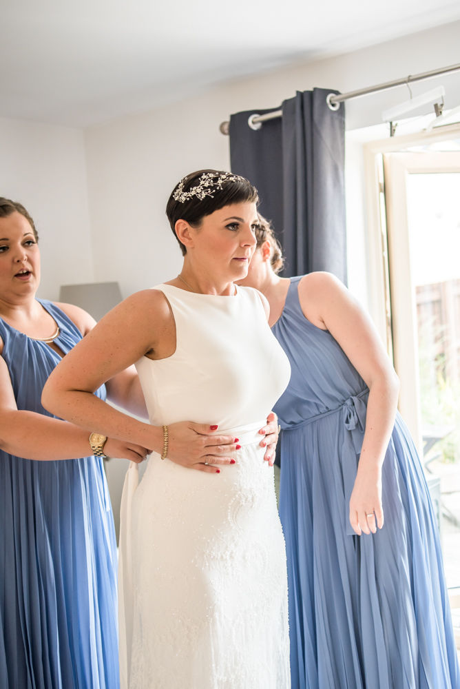 Bride putting dress on with bridesmaids, Sheffield wedding photographer