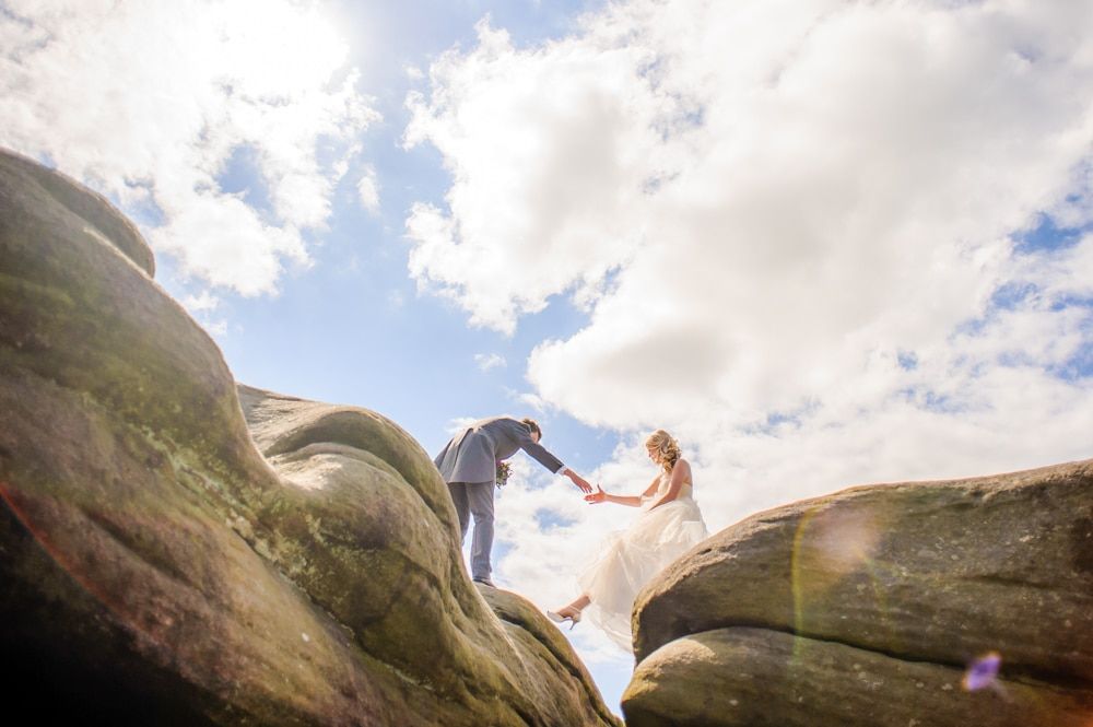 Taking Nick's hand across the rocks, Maynard wedding, Sheffield photographers