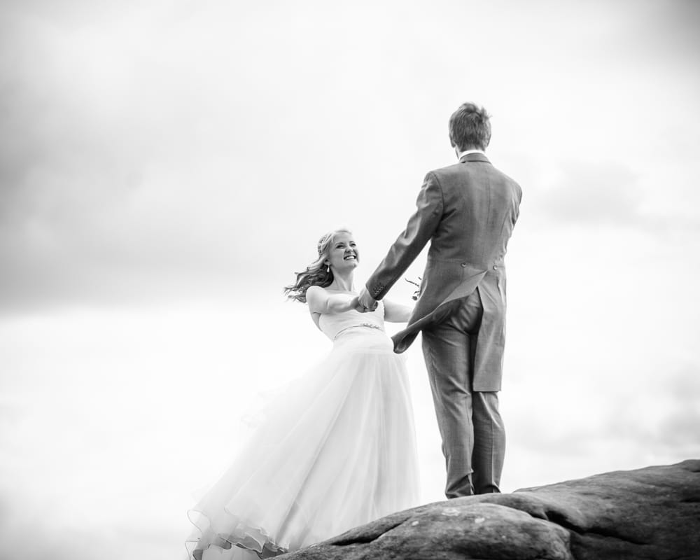 Holding hands on top of Peak District rocks, Maynard wedding, Sheffield photographers