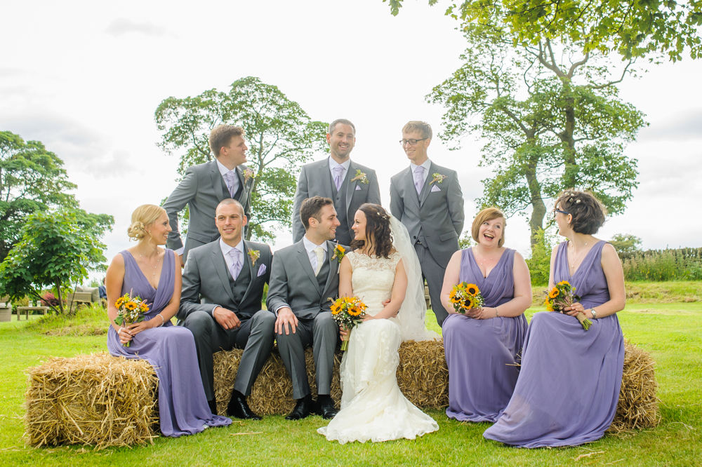Bridal party portrait on hay bales, countryside wedding Lake District