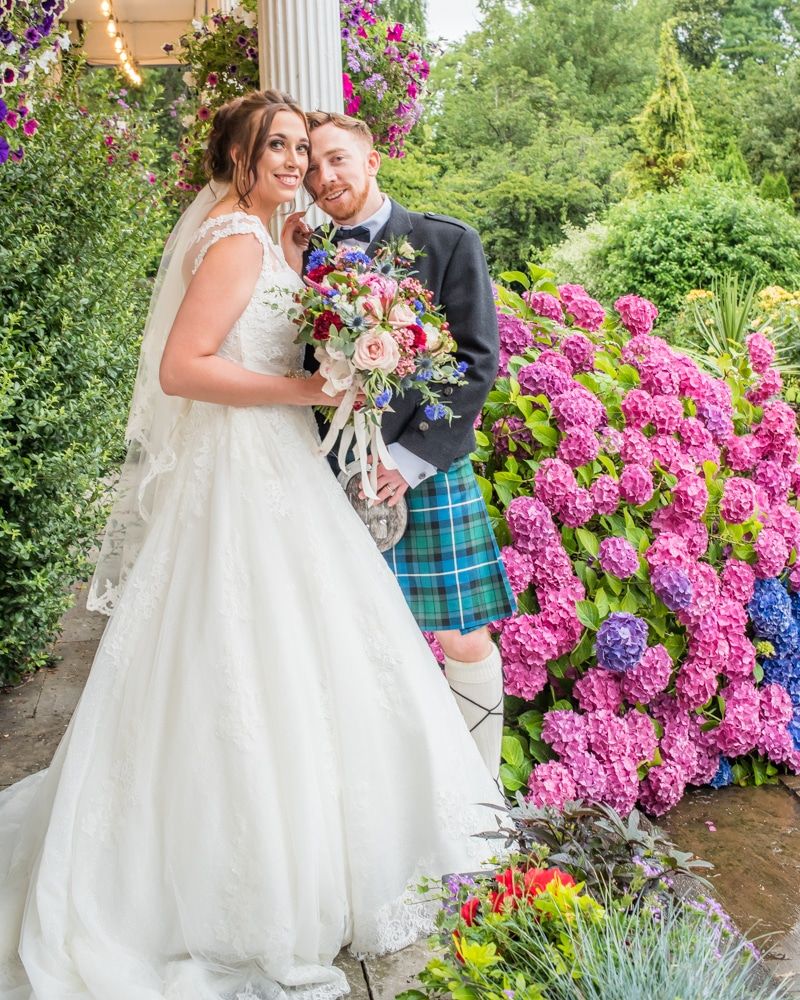 Bride and groom posing by flowers in grounds, Sheffield wedding photographers, Ringwood Hall Hotel
