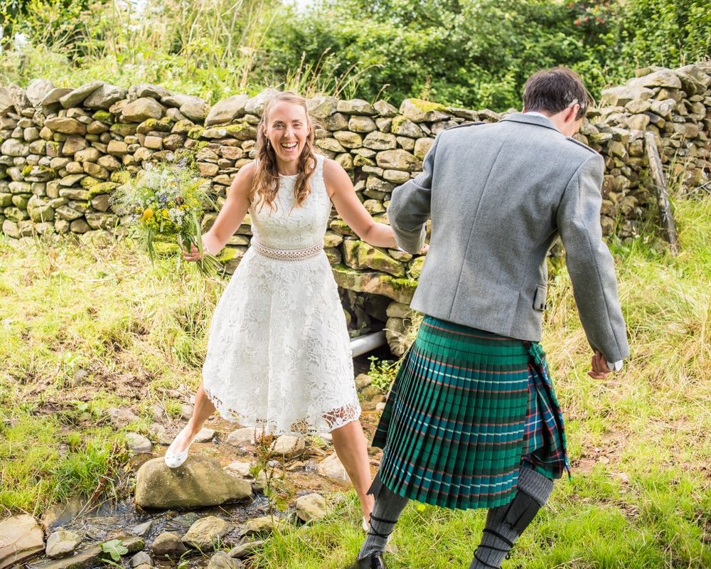 Steve helping Bec over the stream, Howgills wedding, Sedbergh, Lake District wedding photographers