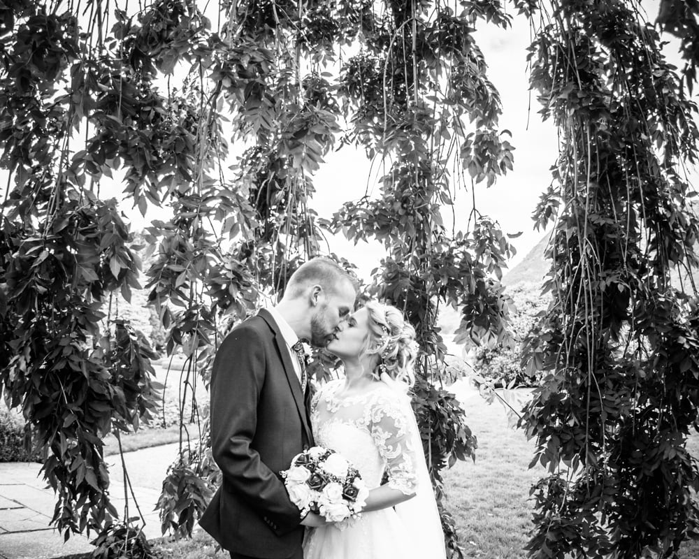 Bride and groom kissing in hotel grounds, Inn on the Lake Weddings, Lake District