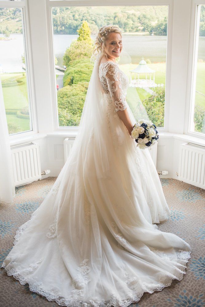 Sarah posing in window with her gown, Inn on the Lake Weddings, Lake District