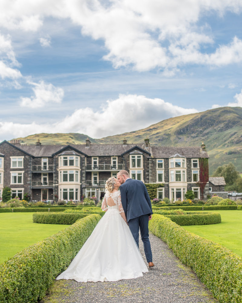 Kisses with hotel in background, Inn on the Lake Weddings, Lake District