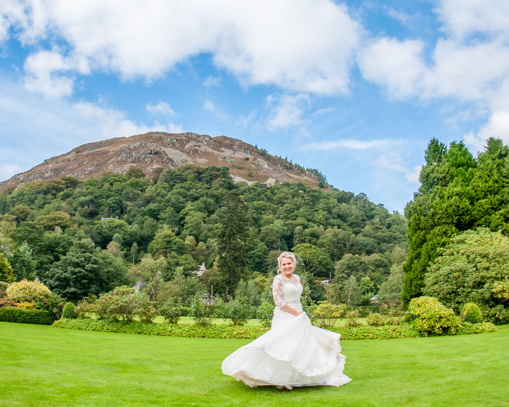 Bride twirling with fells in background, Inn on the Lake, Ullswater, Lake District documentary wedding photographers