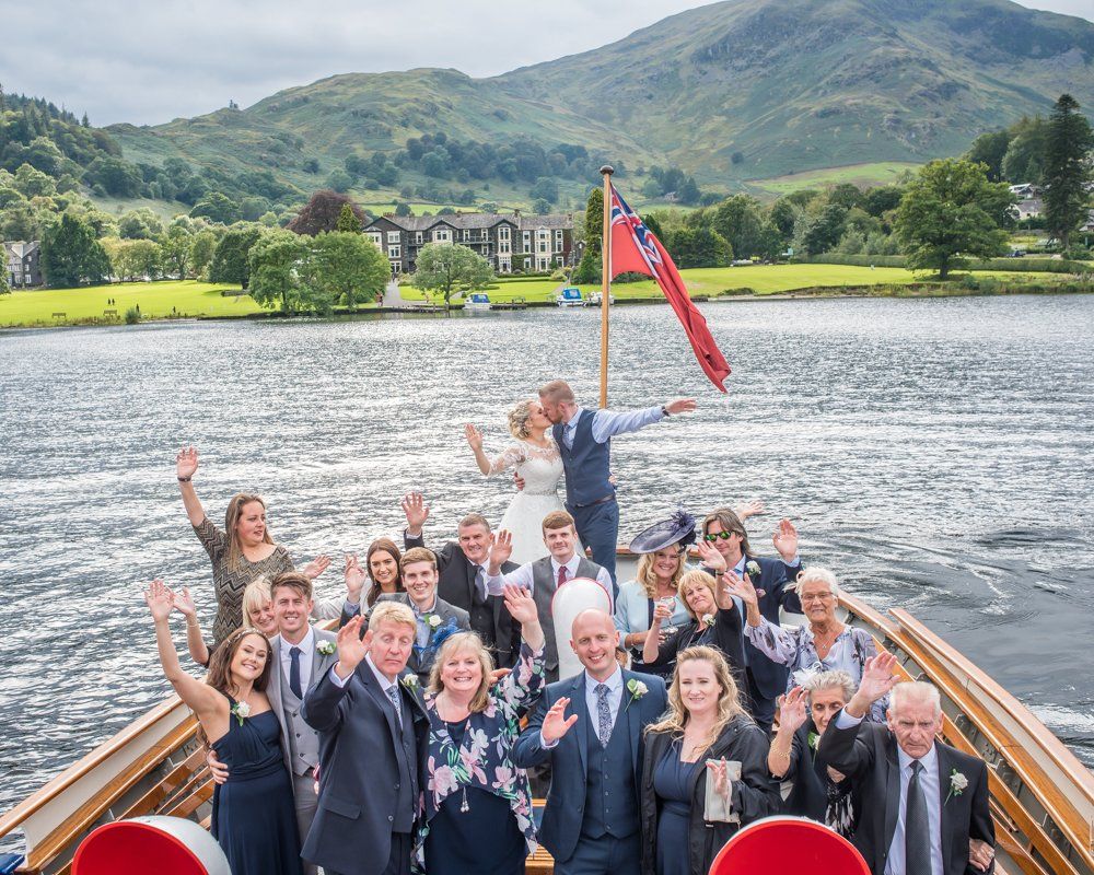 Posing on boat with hotel in background, Inn on the Lake Weddings, Lake District