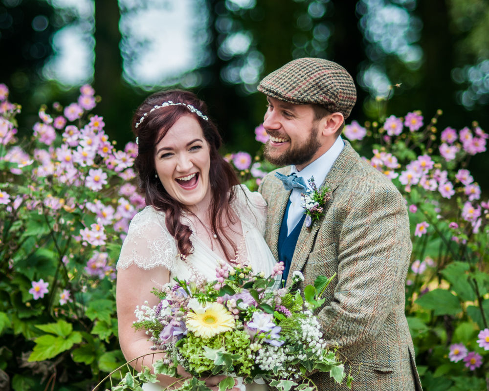 Bride and groom laughing in flowers, natural wedding photography Lake District