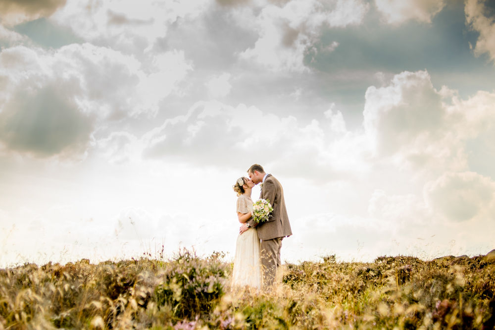Hope & Ben kissing in wild field, Curbar Edge, Peak District wedding photographers Sheffield
