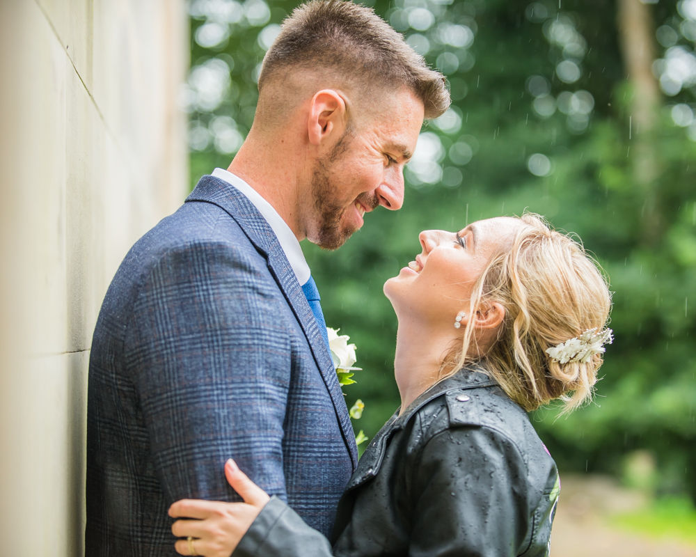 Happy couple laughing in the rain after register office wedding in Carlisle