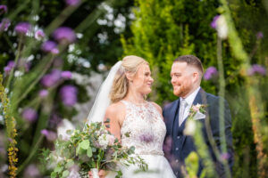 Jess and Robert look at each other through flowers, Castle Green Hotel, Kendal, Cumbria