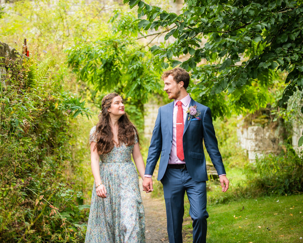 Bride and groom walk through abbey walls, outdoor wedding, Jervaulx Abbey, Yorkshire