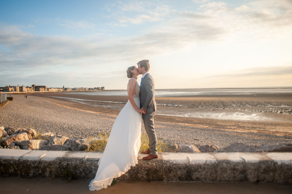 Bride and groom kiss on pier wall, Midland Hotel, Morecambe wedding