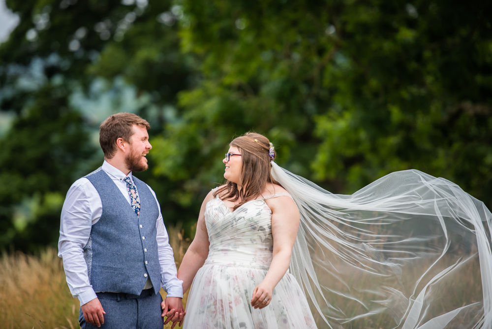 Brides veil blowing in breeze as happy couple laugh, Paddock Barn weddings, Kendal Lake District