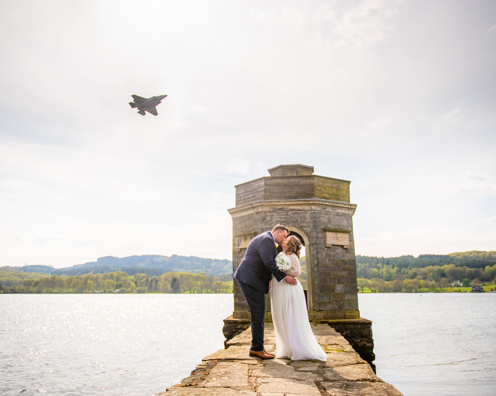 Bride and groom kiss by temple on lake, Storrs Hall elopement wedding, Windermere, Lake District