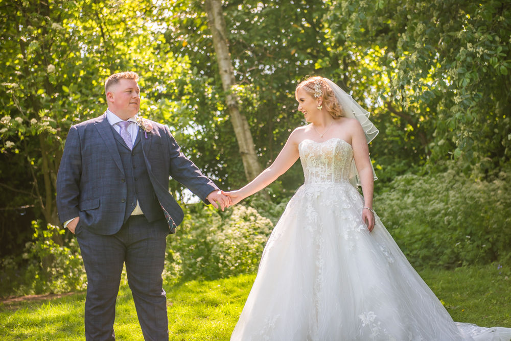 Bride and groom hold hands on grass, Kenwood Hall wedding photography Sheffield